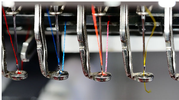 Close view of embroidery machine needles with threads